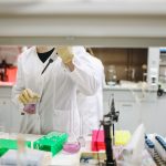 Cientista de jaleco manuseia amostras em um laboratório moderno de pesquisa.