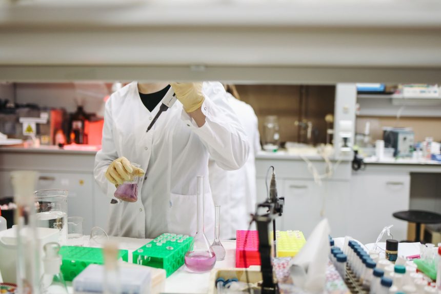Cientista de jaleco manuseia amostras em um laboratório moderno de pesquisa.