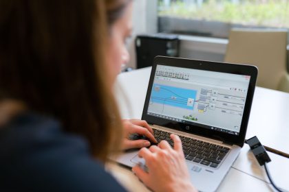 Engenheira analisa software em um laptop durante o trabalho em um ambiente interno.