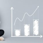 Mulher analisa gráficos e indicadores financeiros em um computador portátil.