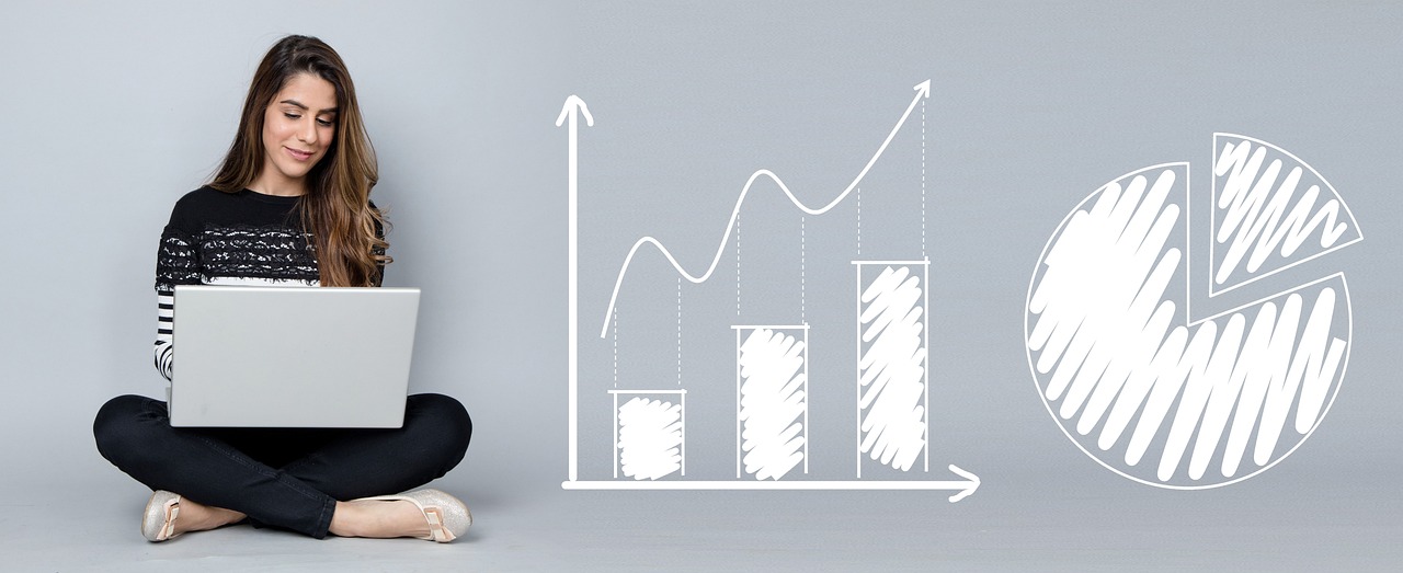 Mulher analisa gráficos e indicadores financeiros em um computador portátil.